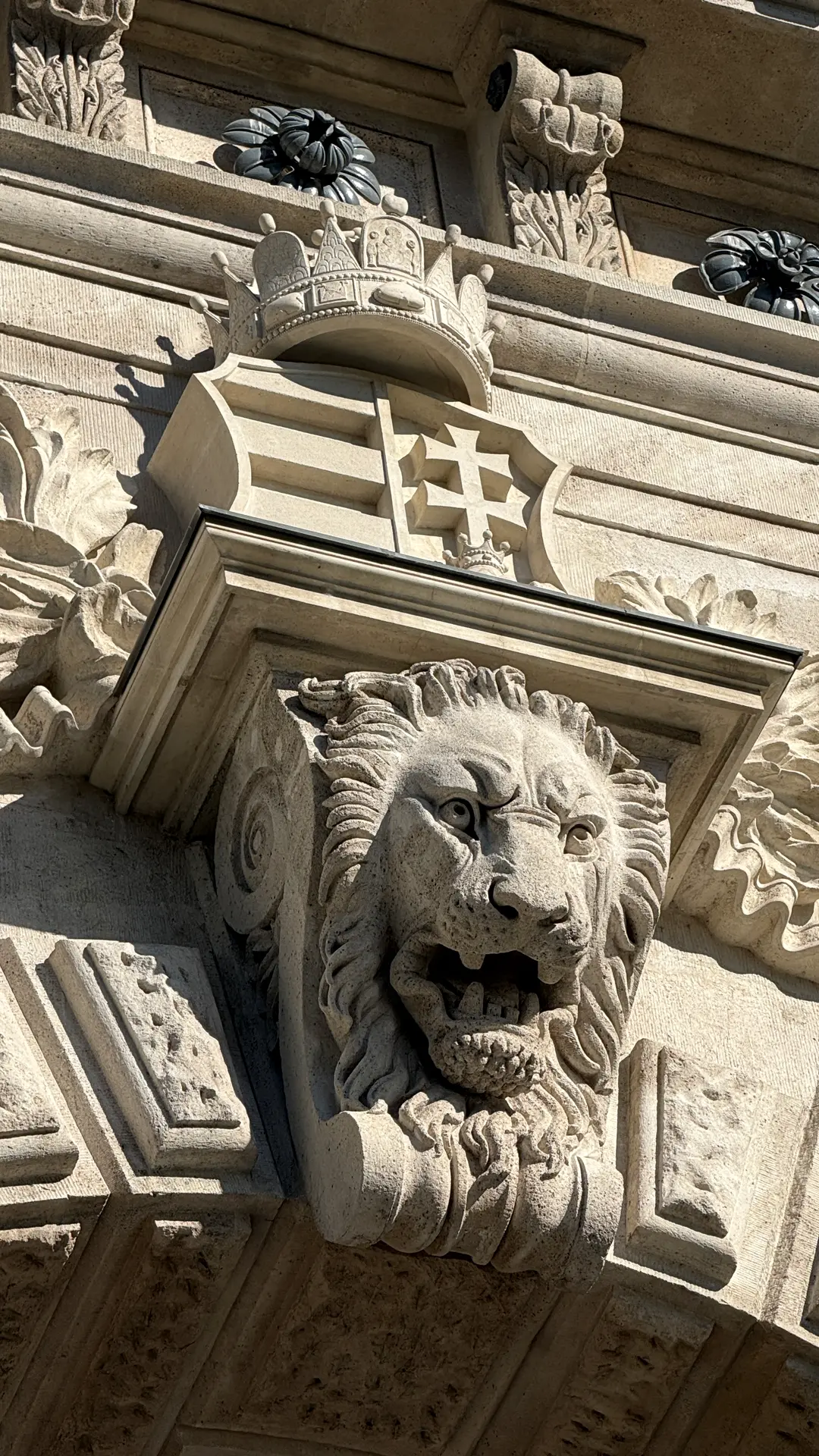 Steinerner Löwenkopf mit Wappen an einer Budapester Fassade