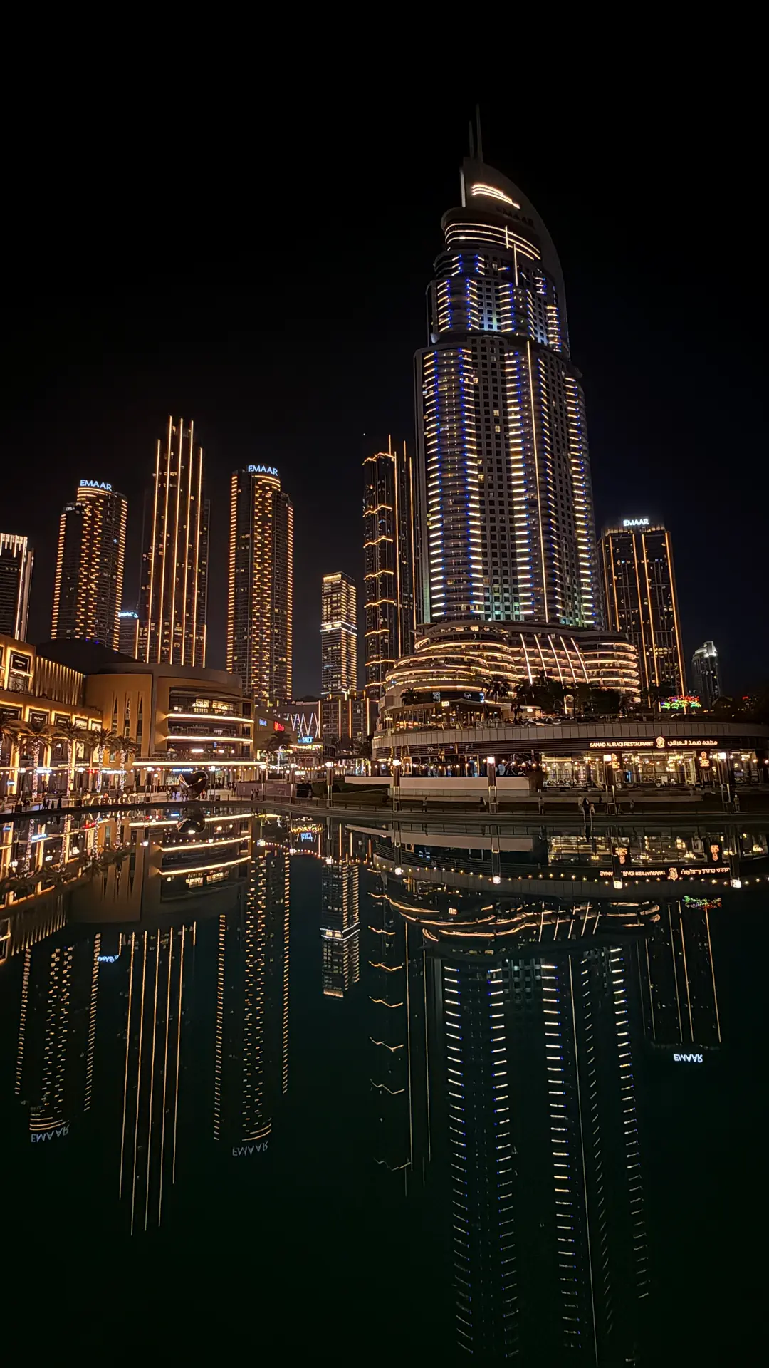 Beleuchtete Hochhäuser von Downtown Dubai spiegeln sich nachts im Wasserbecken