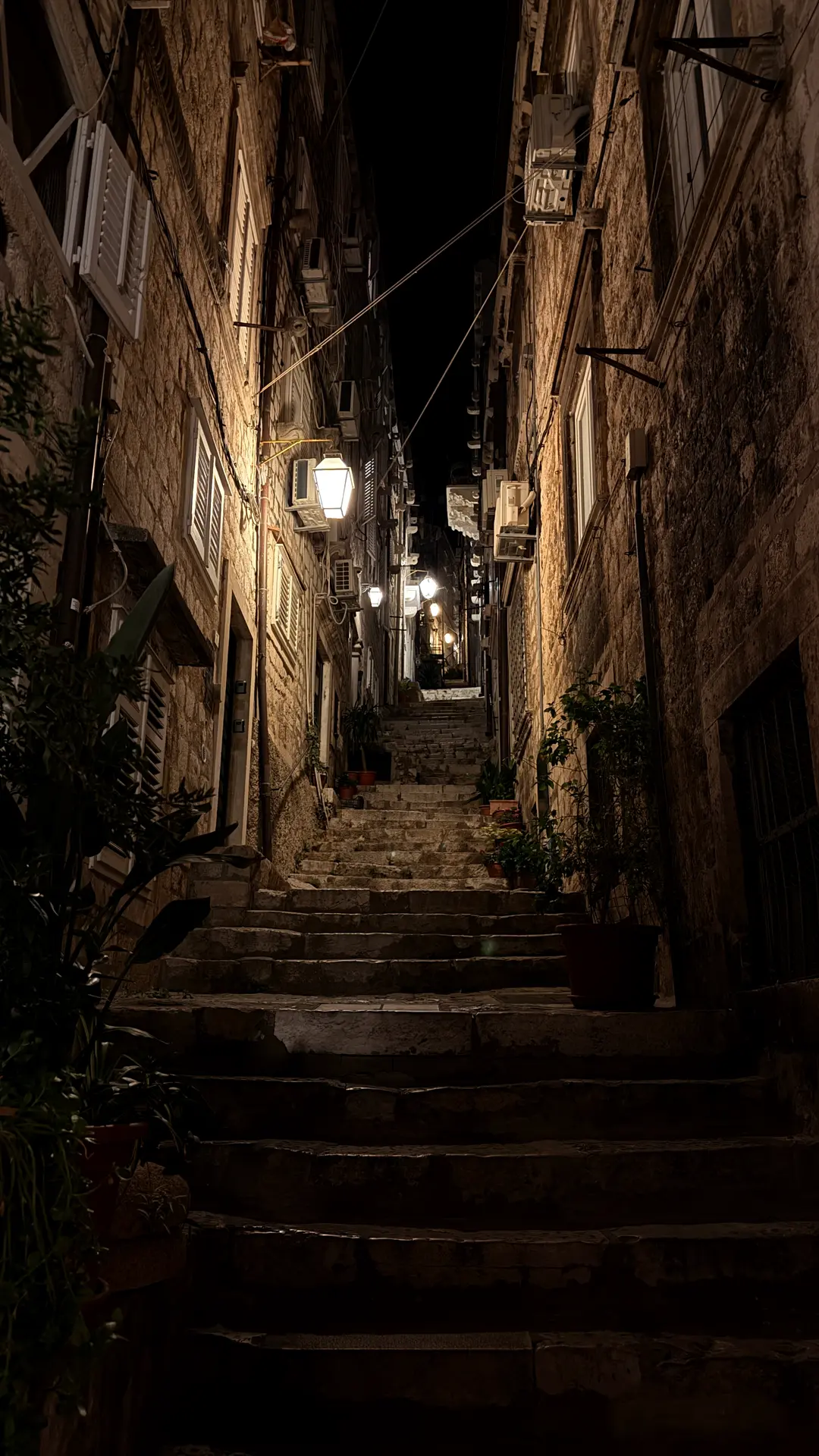 Steile Altstadtgasse mit Treppen und Laternen bei Nacht
