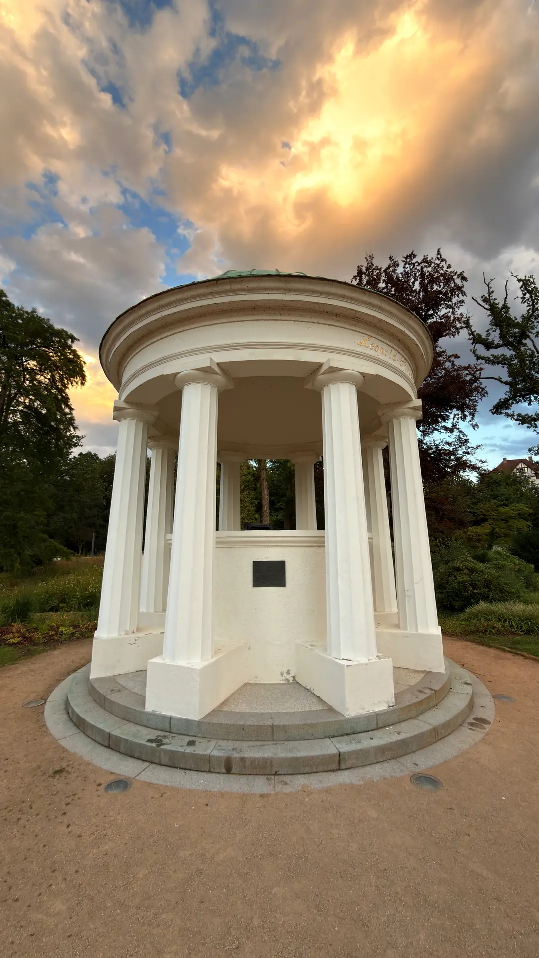 Klassizistischer Rundpavillon mit Säulen unter dramatischem Abendhimmel
