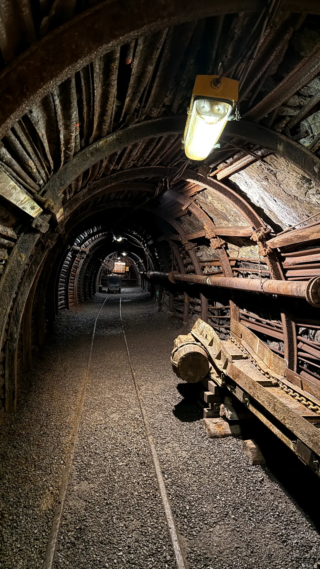 Alter Bergwerksstollen mit Grubenbahn und einzelner Lampe