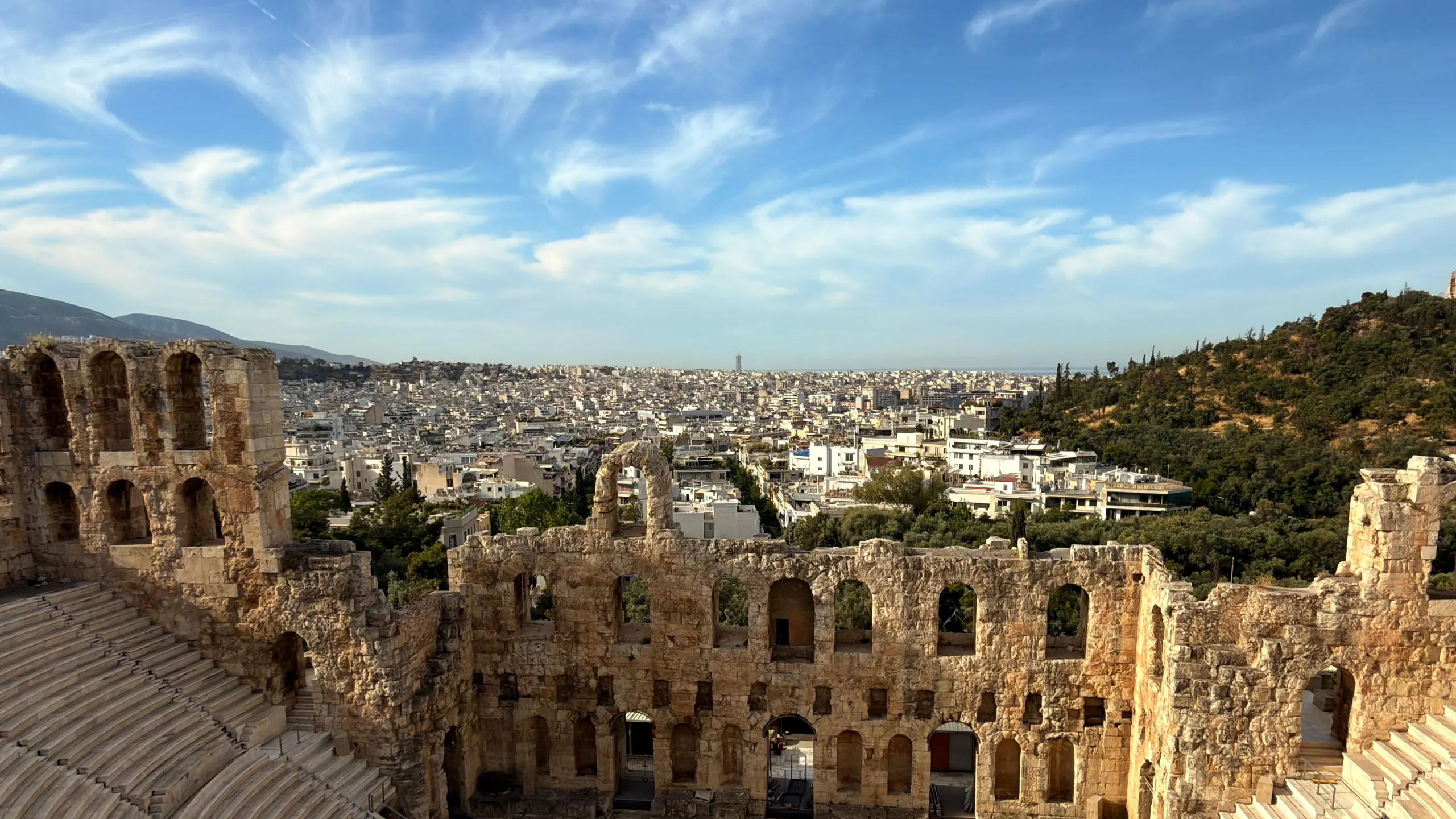 View from above into the ancient Odeon of Herodes Atticus theatre, the sea of Athens rooftops beyond