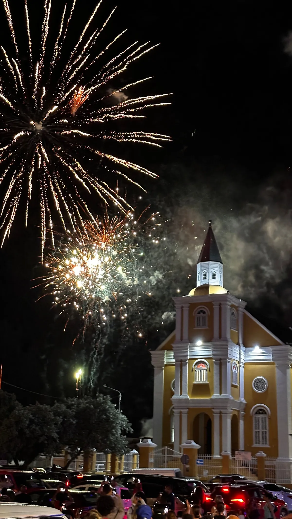 Fireworks bursting above the yellow Fortkerk church in Willemstad at night