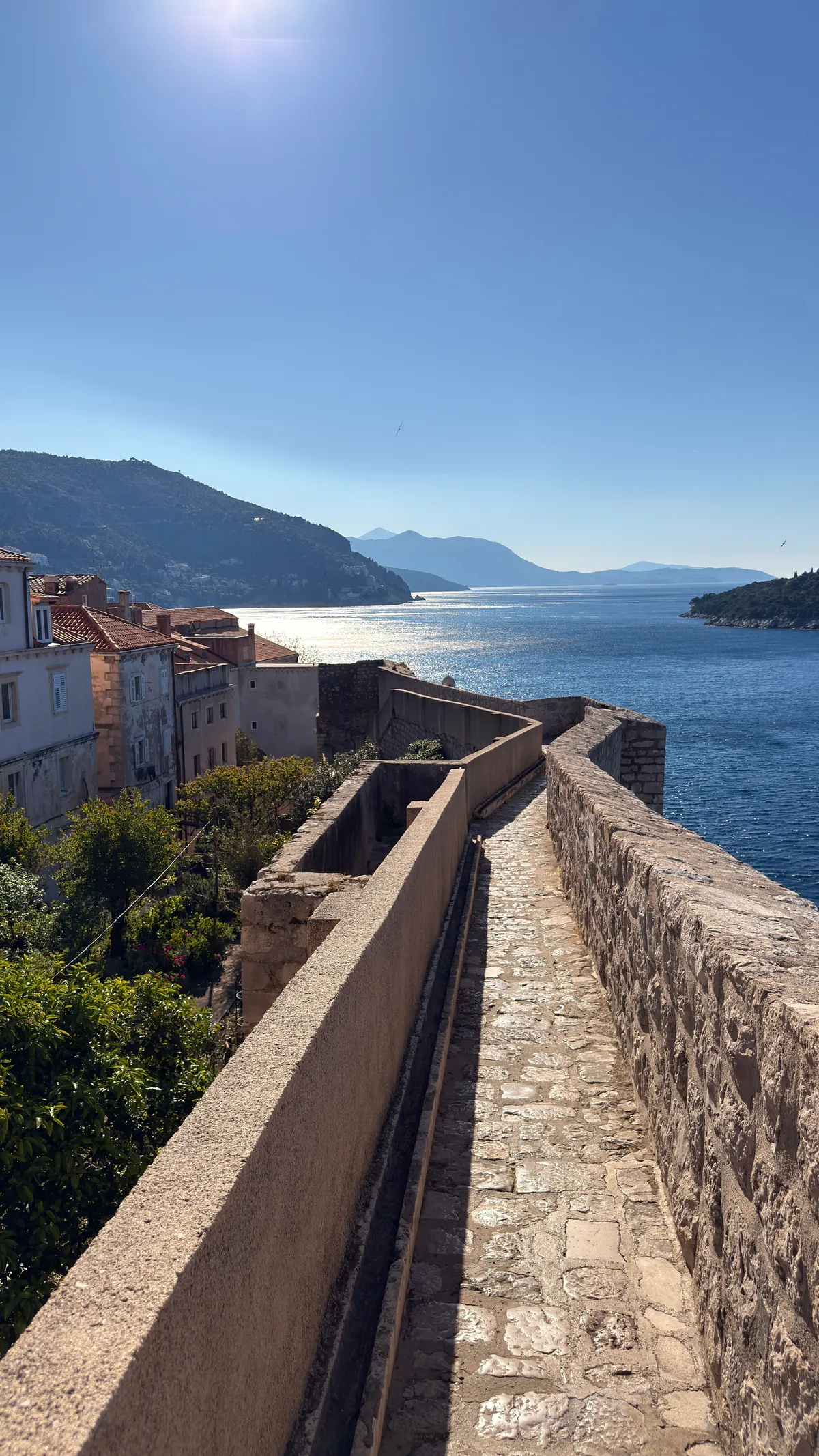 Dubrovnik city wall walkway curving along the coast, the Adriatic and islands beyond