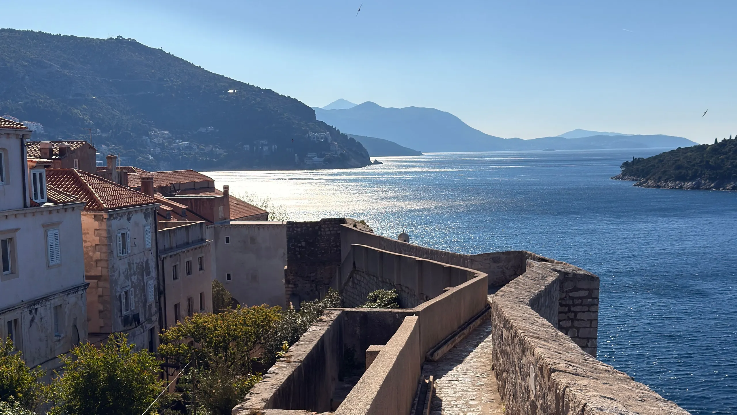 Dubrovnik city wall walkway curving along the coast, the Adriatic and islands beyond