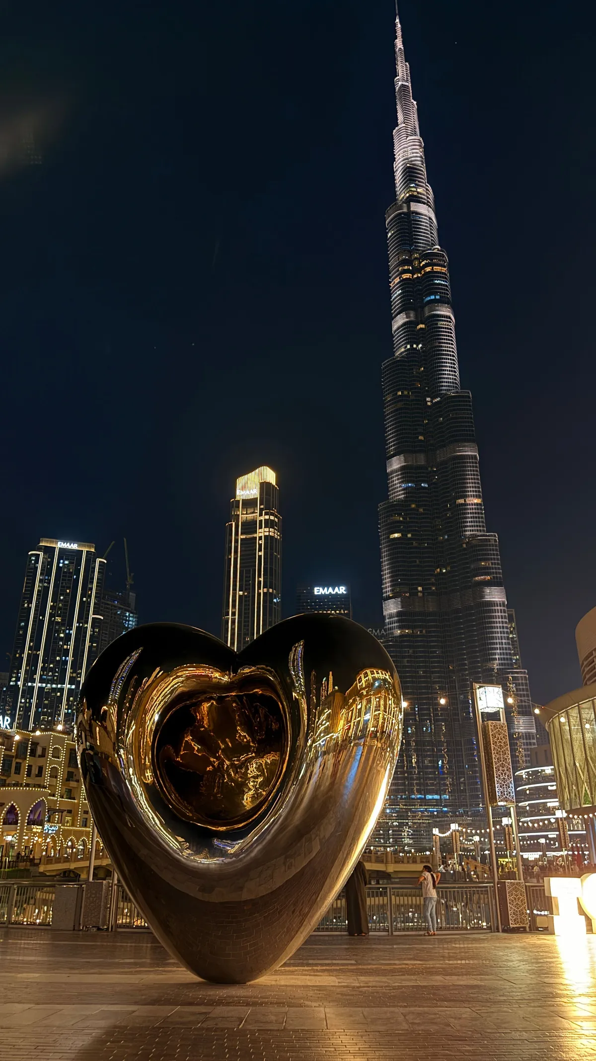Burj Khalifa at night with a mirrored heart sculpture in the foreground