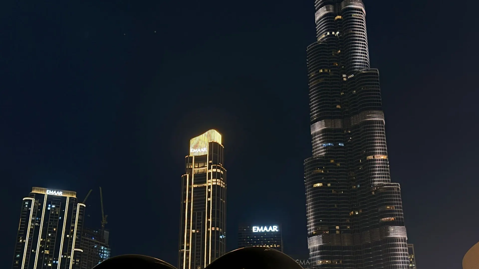 Burj Khalifa at night with a mirrored heart sculpture in the foreground