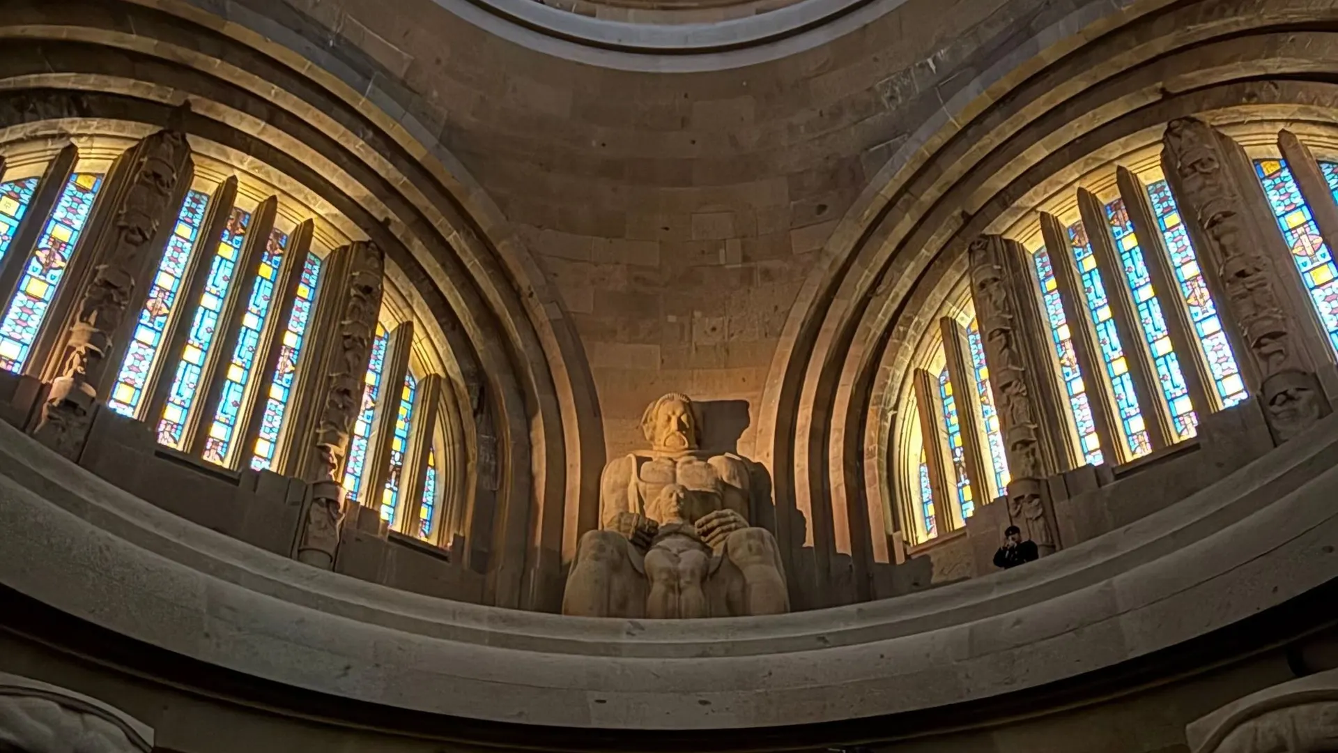 Domed hall of the Monument to the Battle of the Nations with stone guardian figures and rings of light