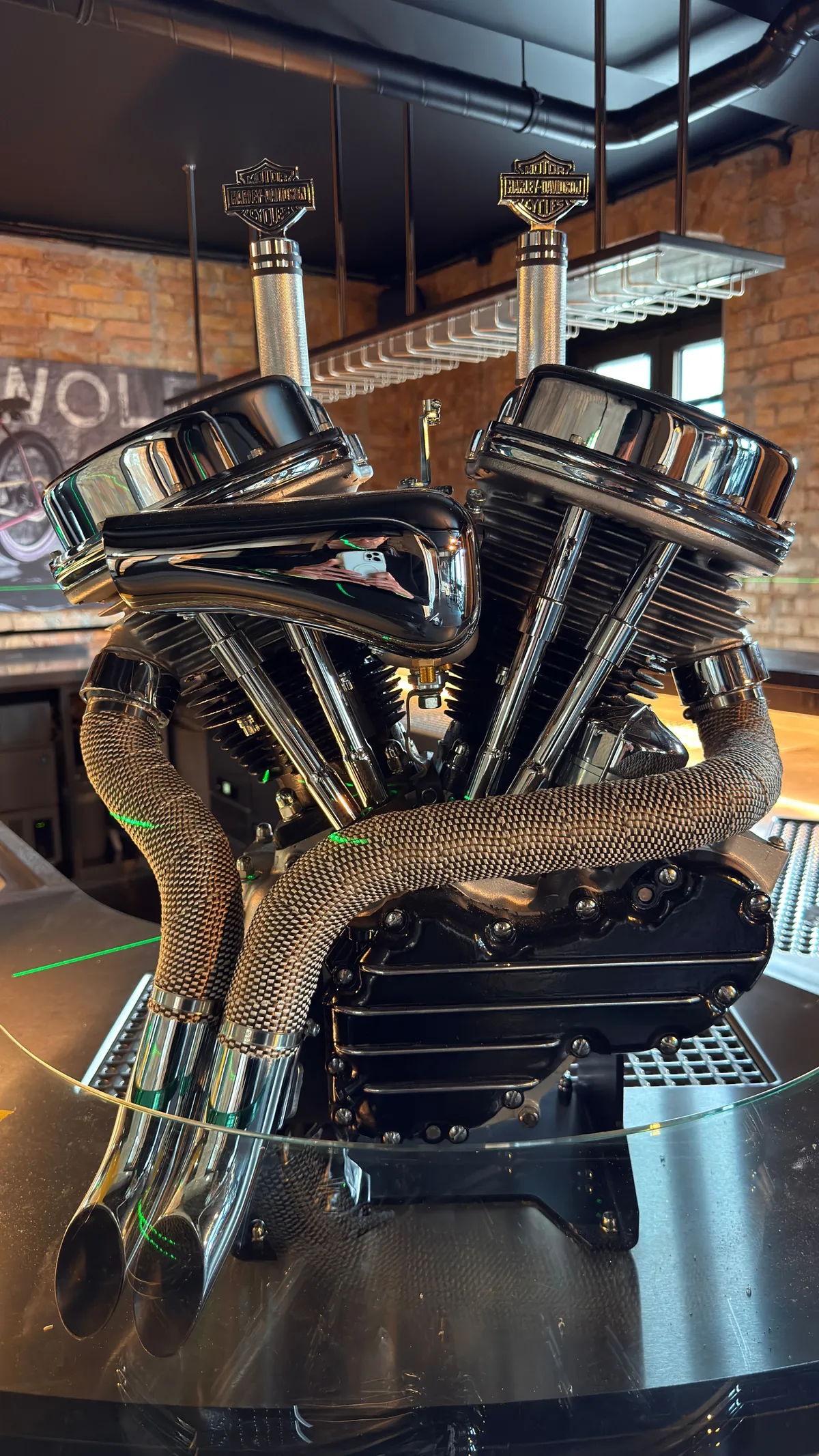 Chrome V-twin motorcycle engine on display in a brick-walled bar