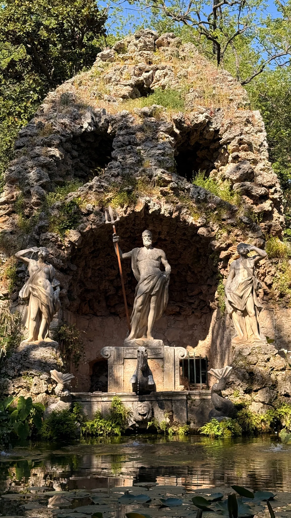 Stone grotto with statues of Neptune and nymphs above a pond with water lilies in the Trsteno Arboretum