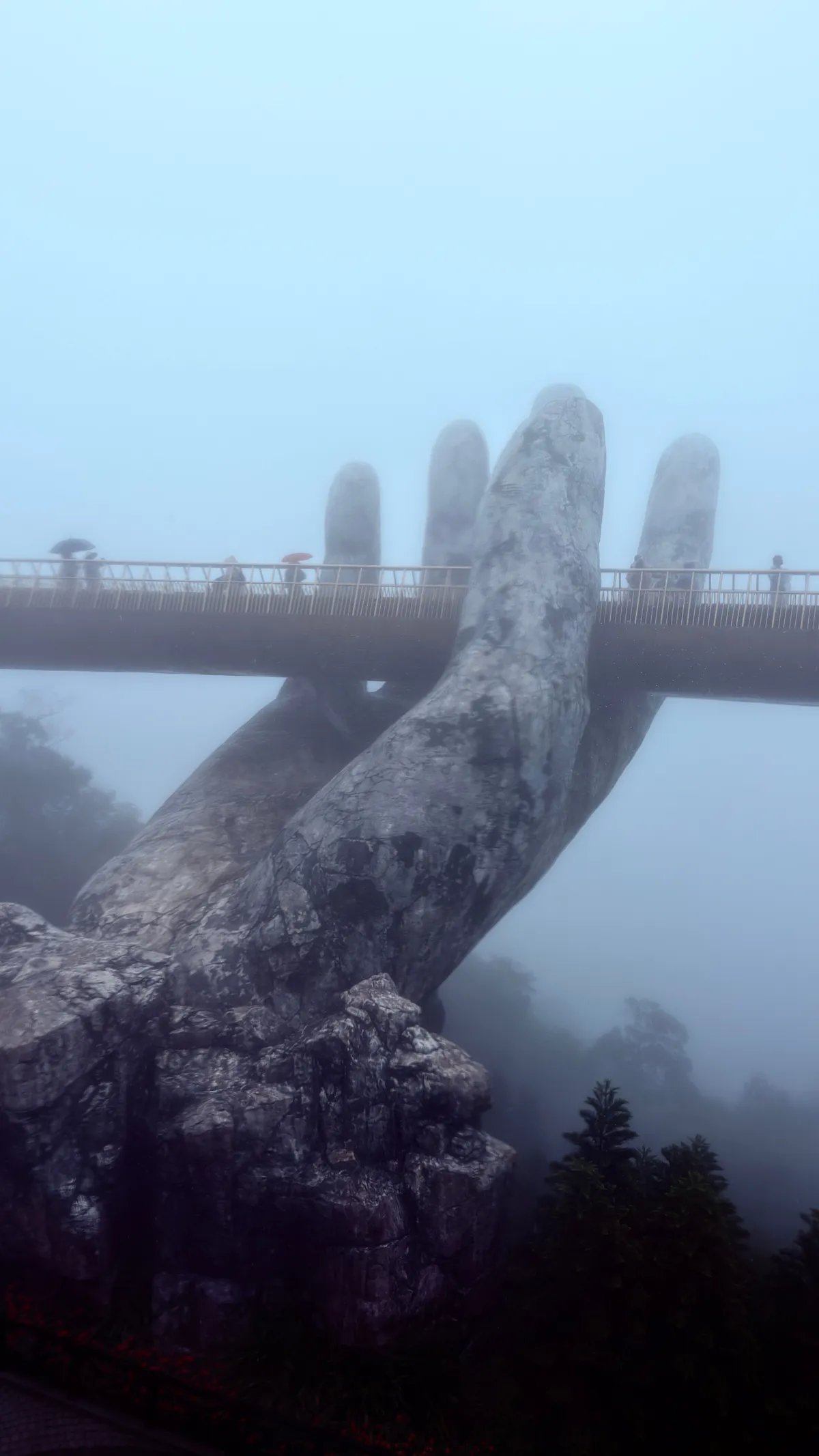 Two weathered giant stone hands lifting the Golden Bridge out of the mist at Ba Na Hills
