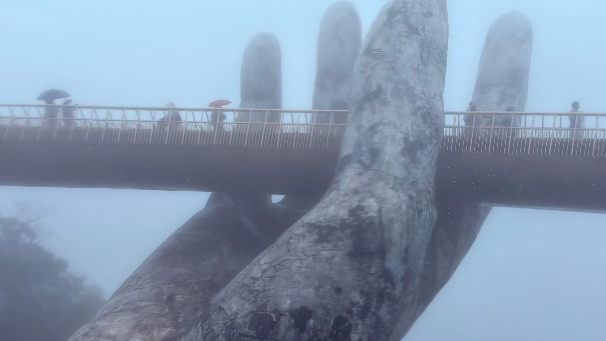 Two weathered giant stone hands lifting the Golden Bridge out of the mist at Ba Na Hills