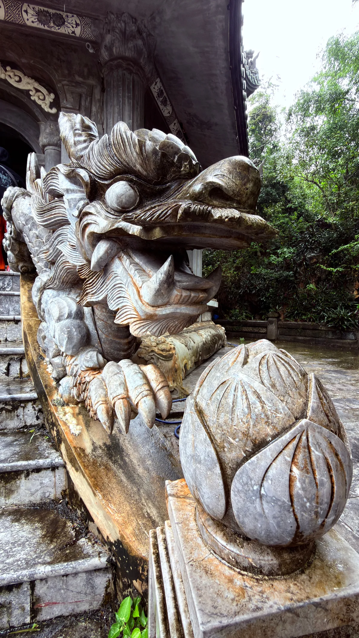 Carved stone dragon head with a lotus bud on a staircase balustrade at the Marble Mountains