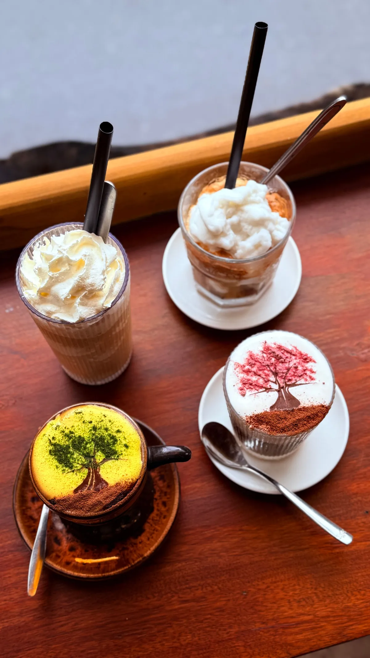 Four Vietnamese coffees on a wooden table: egg coffee, coconut coffee and two with cream and cocoa prints